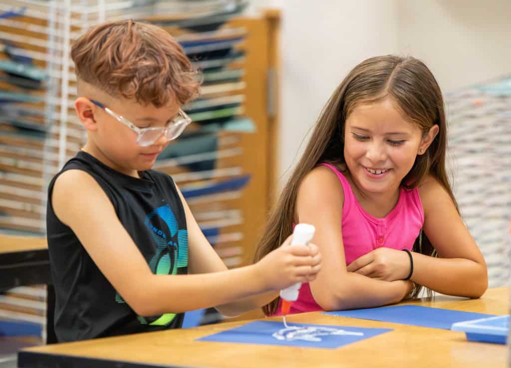 boy and girl smiling and working on art project