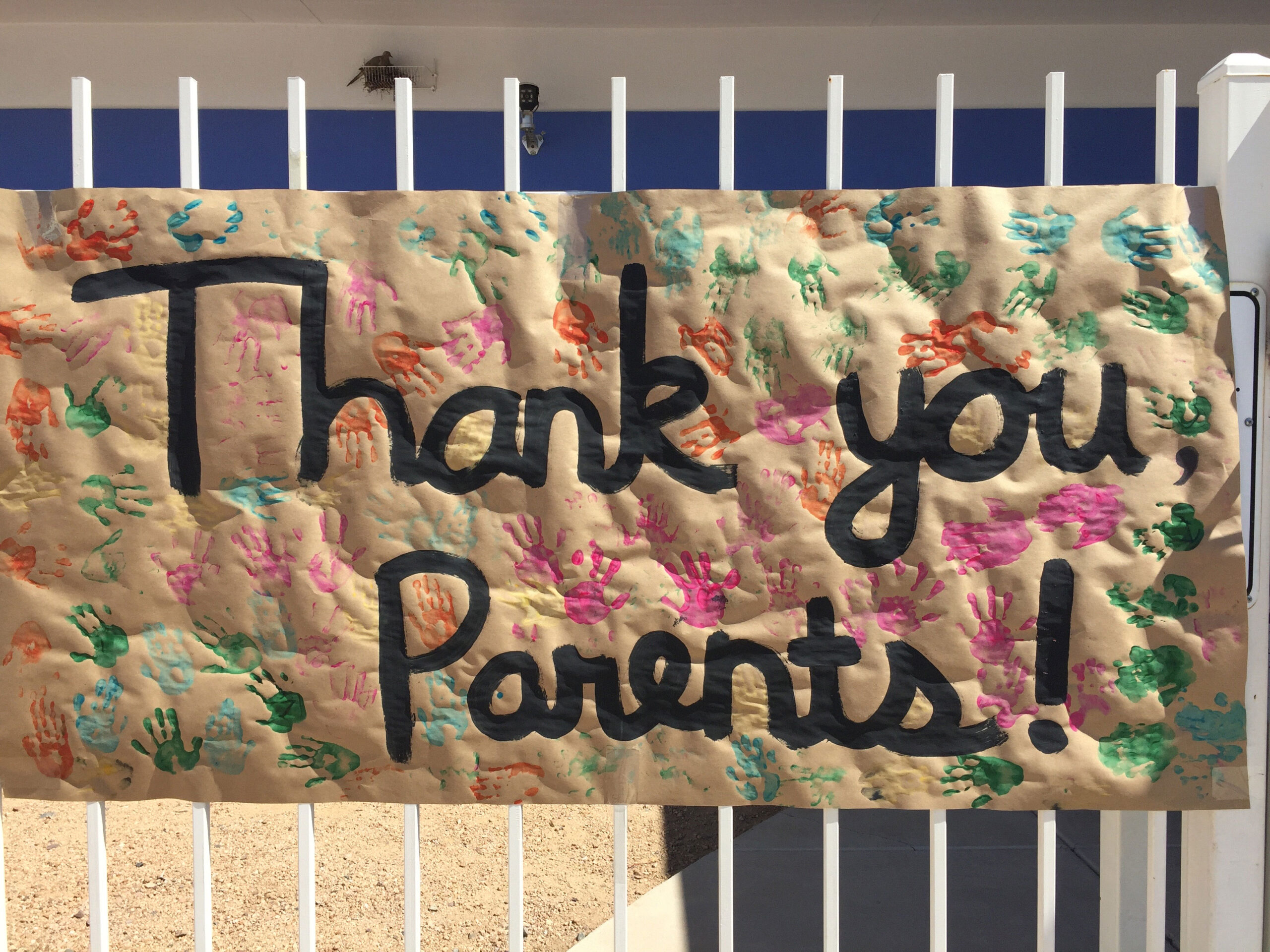 Photo of a butcher paper banner with multi colored handprints.  With the text:  Thank you Parents in black.