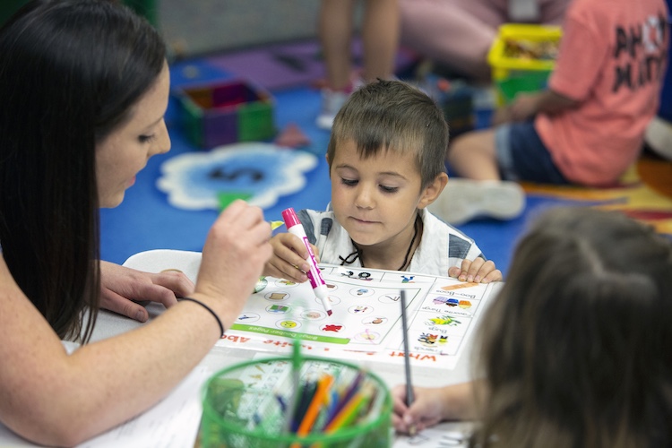 Photo of a small boy and his preschool teacher doing a worksheet.