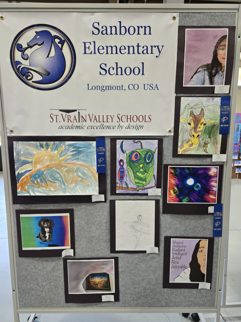 Expositor de arte en Sanborn Elementary en el que se muestran obras de los alumnos, entre las que se incluyen dibujos y pinturas de diversos estilos.